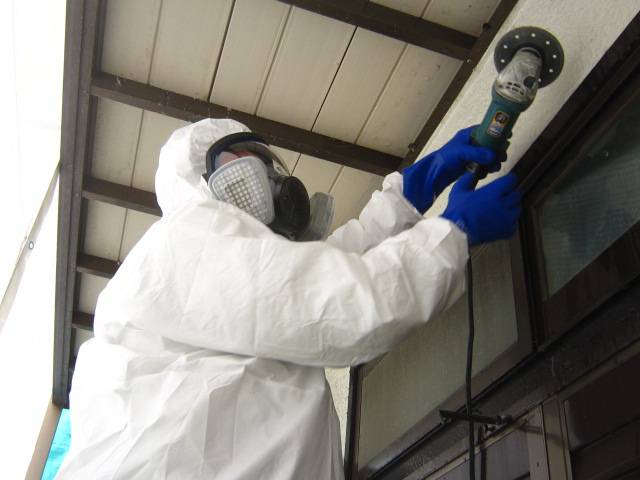 南関東防衛局防音工事：防護服でサッシまわりを電動工具で施工する職人